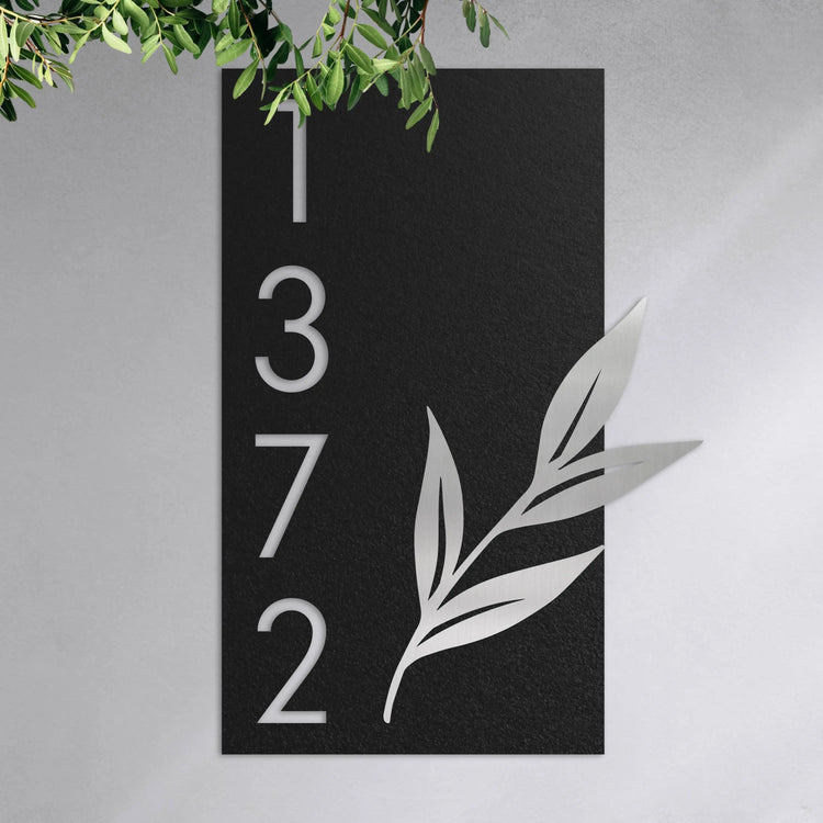 Numéro de maison décoré avec une branche de feuille